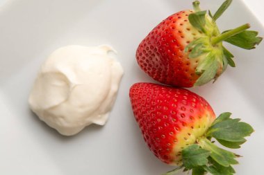 Taze olgun çilek ve krema beyaz Masa arkasında izole