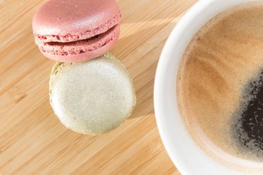 Güneş ışığında ahşap masada kahve ve macaroons