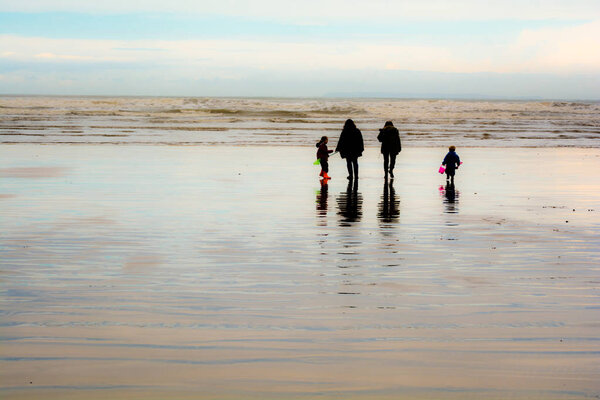 Group of people walking on a sandy beach in wet weather