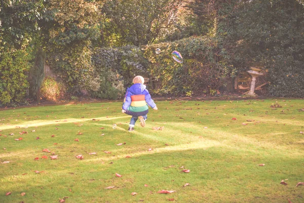 Çocuk gün içinde baloncuklarla bahçede oynuyor. — Stok fotoğraf