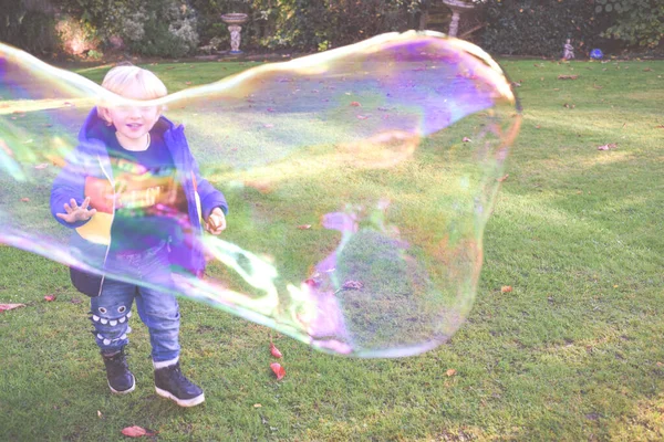 Child playing outside in a garden during day time with bubbles h