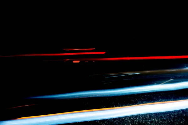 Sentiers lumineux des voitures passant par un tunnel sombre sur un terrain pluvieux — Photo