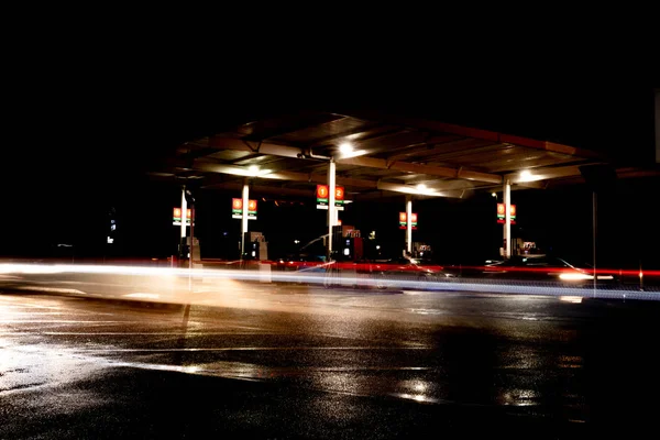 사람들 주유소에 휘발유를 지나가는 자동차에서 나오는 불빛으로 주유소를 드린다 — 스톡 사진