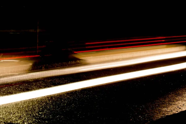 Trilhas de luz de carros que passam por um túnel escuro em um chuvoso — Fotografia de Stock