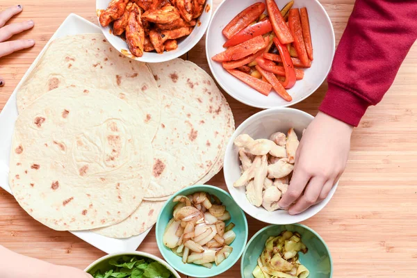 Kids choose what to add to homemade tortilla ingredients at chil