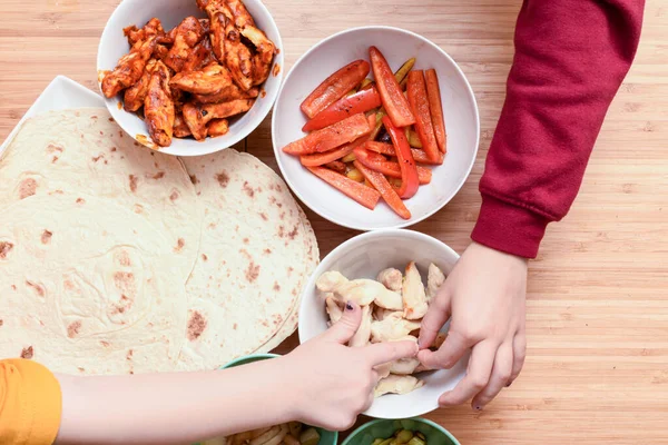 Kids choose what to add to homemade tortilla ingredients at chil