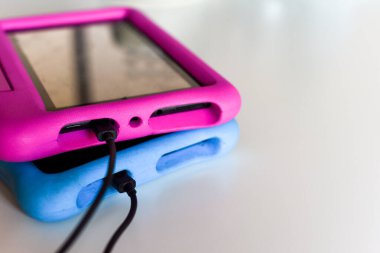 Oyun oynamak için iki çocuk tableti ve güç kaynağı kablosuna takılı eğitim uygulamaları