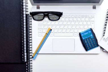 Ofis masası kalem bilgisayarı ve not defterleriyle dolu.