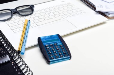 Ofis masası kalem bilgisayarı ve not defterleriyle dolu.