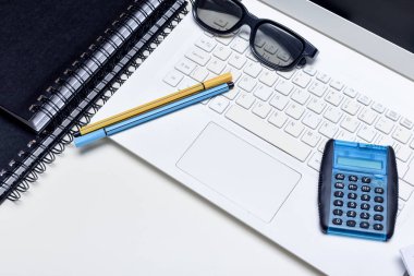 Ofis masası kalem bilgisayarı ve not defterleriyle dolu.