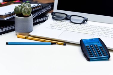 Ofis masası kalem bilgisayarı ve not defterleriyle dolu.