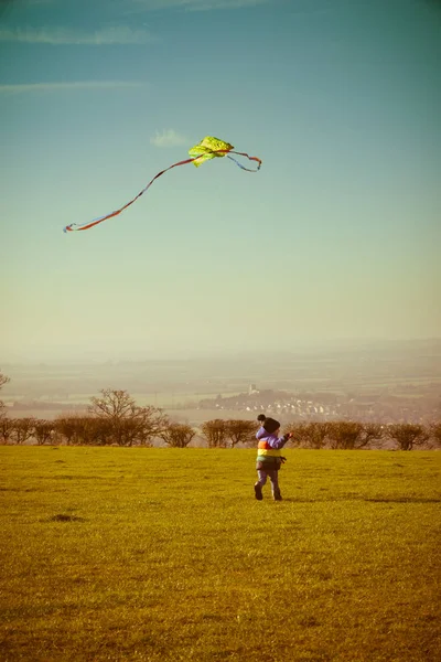 Jongen die buiten met een vlieger speelt, overdag buiten rent — Stockfoto