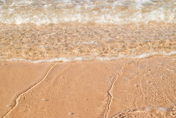 Неглибока вода на березі, як ніжні хвилі розбиваються над теплим віолончелем — стокове фото