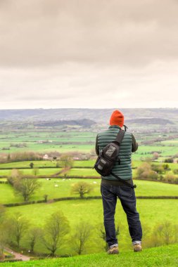 A man looks out over hills to take a photograph during an advent