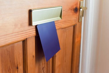Blank leaflet or flyer being posted through a letter box unwante