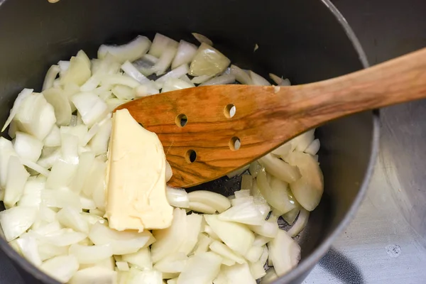 Готовить свеженарезанный лук с маслом на соуте в кастрюле — стоковое фото