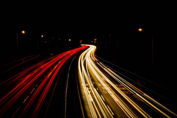 Trilhas de luz de faróis de carro em movimento e luzes de veículo traseiro — Fotografia de Stock