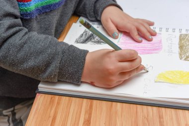 Evde çocuk eğitimi. Okul öncesi çocuk şekilleri ve el yazısını öğreniyor.