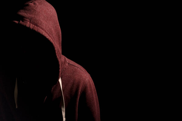 Faceless man in a hoody in dark shadows to disguise face
