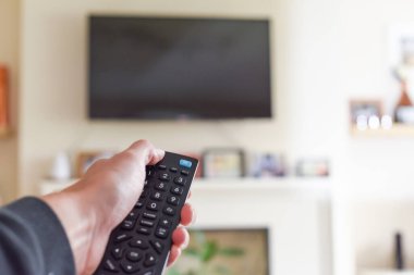 Evde televizyonu açan uzaktan kumandalı bir el.