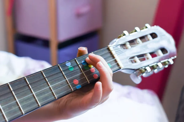 一个女孩在家里学习手拉手弹吉他 — 图库照片