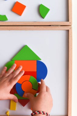 Çocuk renkli bulmaca oyuncaklarıyla oynuyor evde öğrenmek için şekiller yapıyor