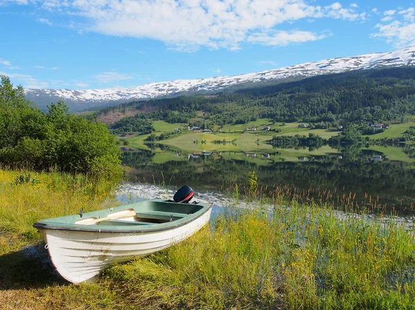 Barco en hermoso lago claro en Noruega. Montañas nevadas en el fondo — Foto de Stock