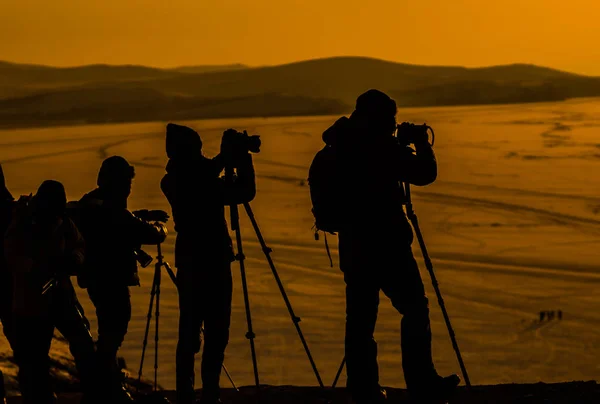 silhouettes of photographers, with their equipment , shooting a sunset