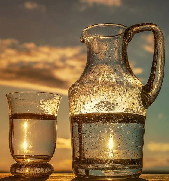 Glass  of  Water and  Pitcher, on blue sky  background,  outdoors, vertical, toning.