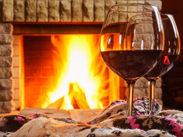 Red wine  in  glasses , wool things, before  cozy fireplace, in country house, winter vacation.