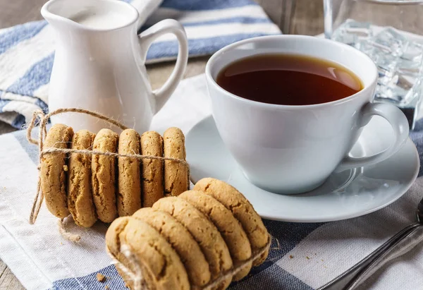 Chip cookies, a cup of tea,  sugar, milk, glass of ice water.