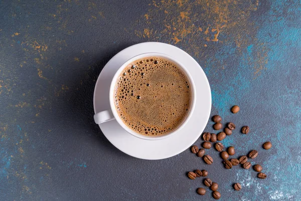 Black coffee with foam in a cup and coffee beans, on blue concrete background.,flat lay.