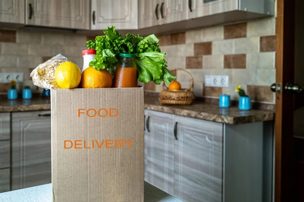 Safe food delivery to your home. A box with various products-milk, fruit and vegetables in a modern kitchen.