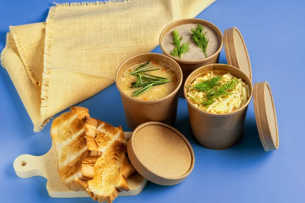 Pea, Mushroom and chicken soup in paper disposable cups for take-out or delivery of food on a blue background.