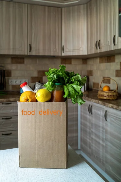 Safe food delivery to home. A box with various products-milk, fruit and vegetables in a modern kitchen.