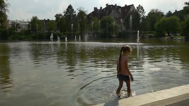 Petite fille marche près de la rive d'un lac peu profond — Video