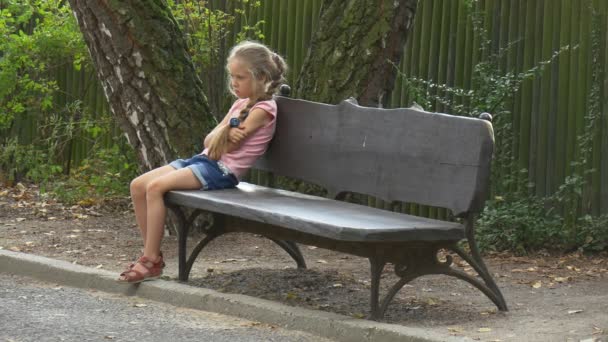 Liten flicka väntar på en föräldrar nära en bänk — Stockvideo