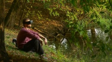 Adam açık havada 360vr gözlük izlerken Video 360 derece oturan Park tarafından su oynarken sanal oyunlarda güneşli gün alır Off gözlük kalkar