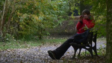 Gözlüklü Adam Park 'taki bir bankta dinleniyor Gözlüklerini çıkarıyor Ağaçlar Ormanı' na bakıyor Kuru Yapraklar Sonbahar Gününde Turist Yaprakları