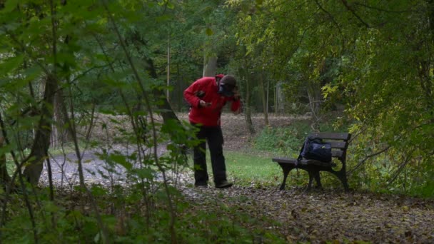 Чоловік у 360vr окулярах стоять дивляться відео 360 градусів ігри віртуальний Ігри сидить вниз на лавці зачарований з відео хмарний день парк алея падіння — стокове відео