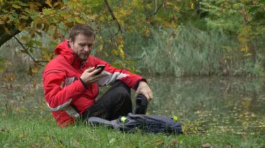 Adam izlemek Video 360 derece vr gözlük oynarken sanal oyunlar alır kulaklık kapalı ve onun gözlük dinlenme bulutlu gün Park su üzerine koyar
