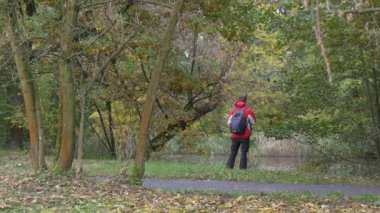 Sonbahar parkında sırt çantalı bir adam.