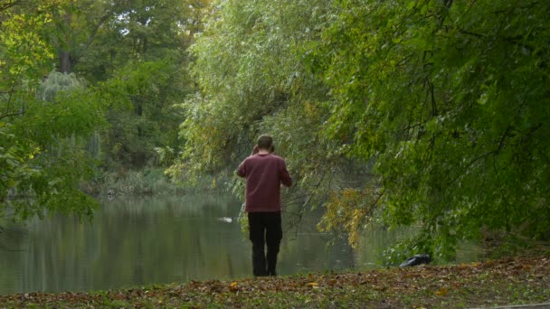 Man in 360Vr Helmet Walking by Lake Bank Autumn Landscape Tourist Sits Down Watching Video 360 Degrees Playing Virtual Games Cloudy Day Park by the Water — Stockvideo