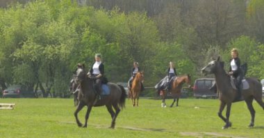 Opole, Poland - May 02 2016: Several Women Riders in Black and White Clothes. Women on Horseback in the Background of Trees and Parked Cars.