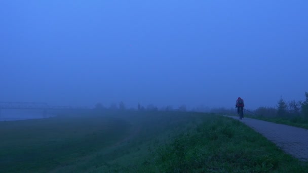 Cyklista. Ranní procházka podél řeky. Podzimní mlha — Stock video