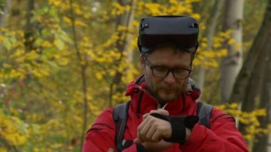 Man in 360Vr Glasses Touches Imaginary Object Watching Video 360 Degrees Playing Virtual Games in Park in Autumn Yellow Leaves Backpacker is Resting