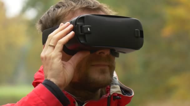 Man kijken Video 360 graden in 360vr bril buiten spelen virtuele spelen in herfst bewolkte dag gele bomen Backpacker is rust in de natuur — Stockvideo