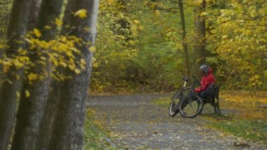 Turist gelir oturur aşağı Park Bisiklet yer tezgah sonbahar günü bisikletçi tezgah için dinlenme arasında altın ağaçları yere sarı yaprakları ile kaplı olduğunu