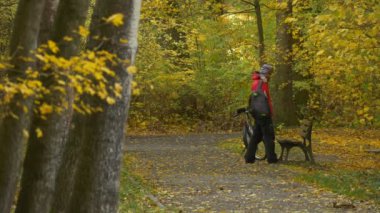 Dostum üzerinden yedekte bir Bisiklet Park sonbahar günü bisikletçi tarafından yukarı alır dinlenme arasında altın ağaçlarda Park patika zemin sarı yaprakları ile kaplı olduğunu