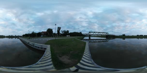 360vr Video most přes řeku Oder Pier budovy Oder hladké vody krajinou za soumraku Cloudscape zelený trávník střílení během modré hodiny večer — Stock video